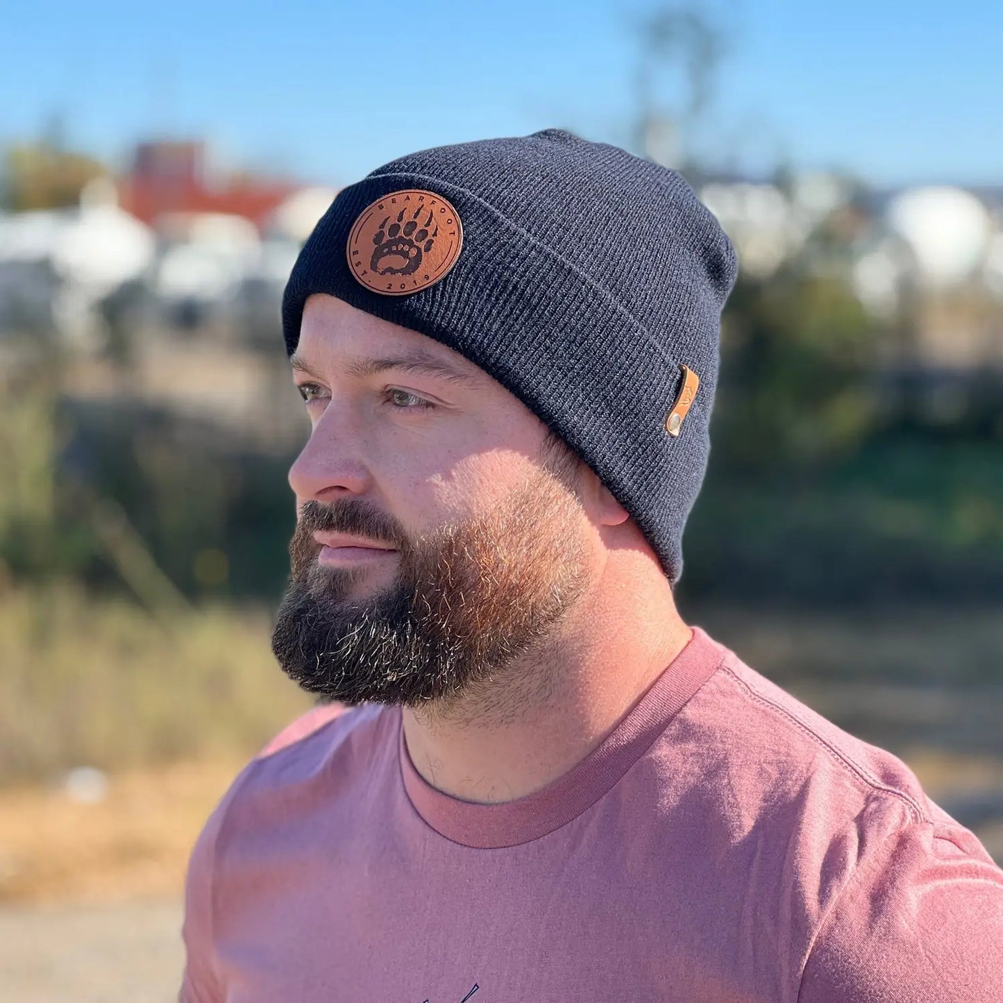 Navy blue wool beanie with full-grain leather patch design and orange stitching